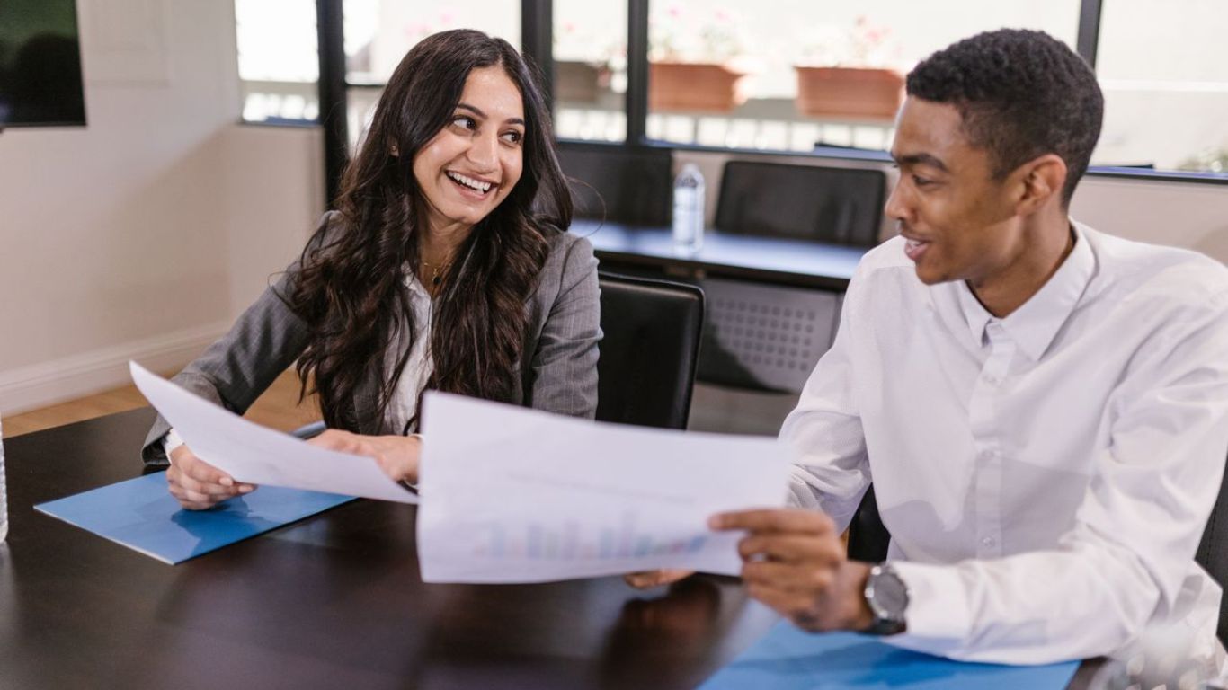 Business colleagues smiling and reviewing financial report