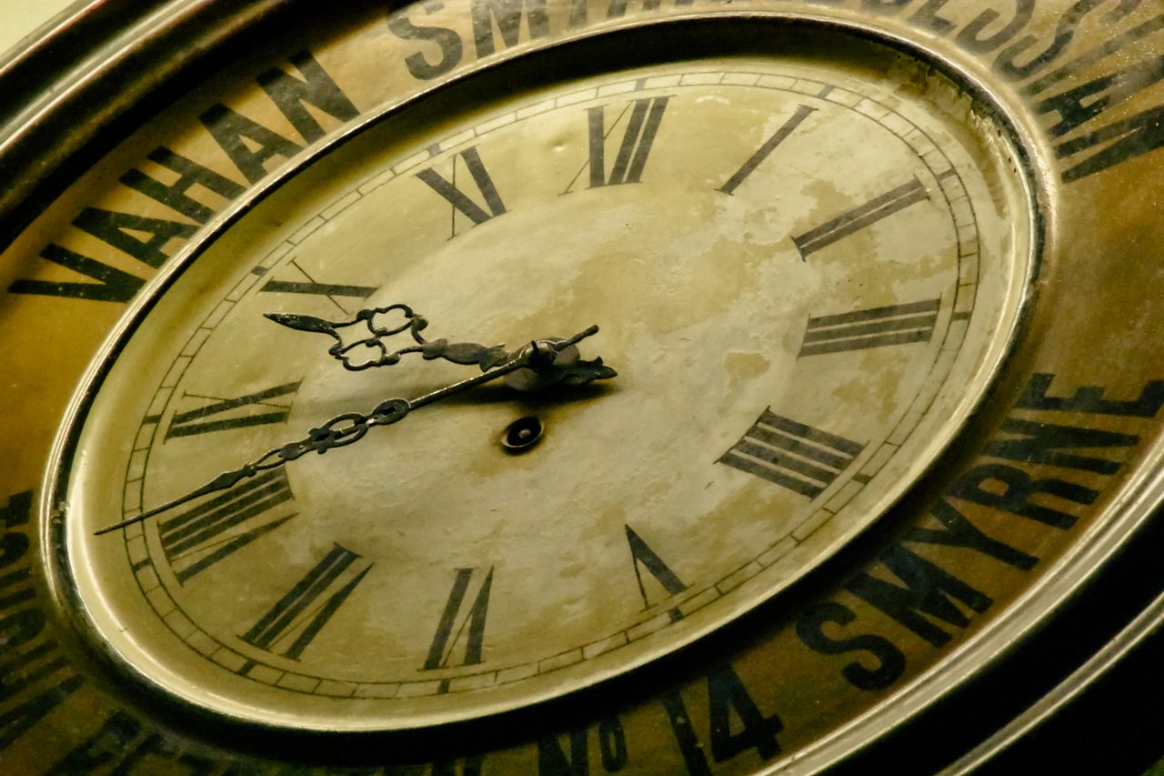 Antique mechanical clock dial showing winding points and ornate hands