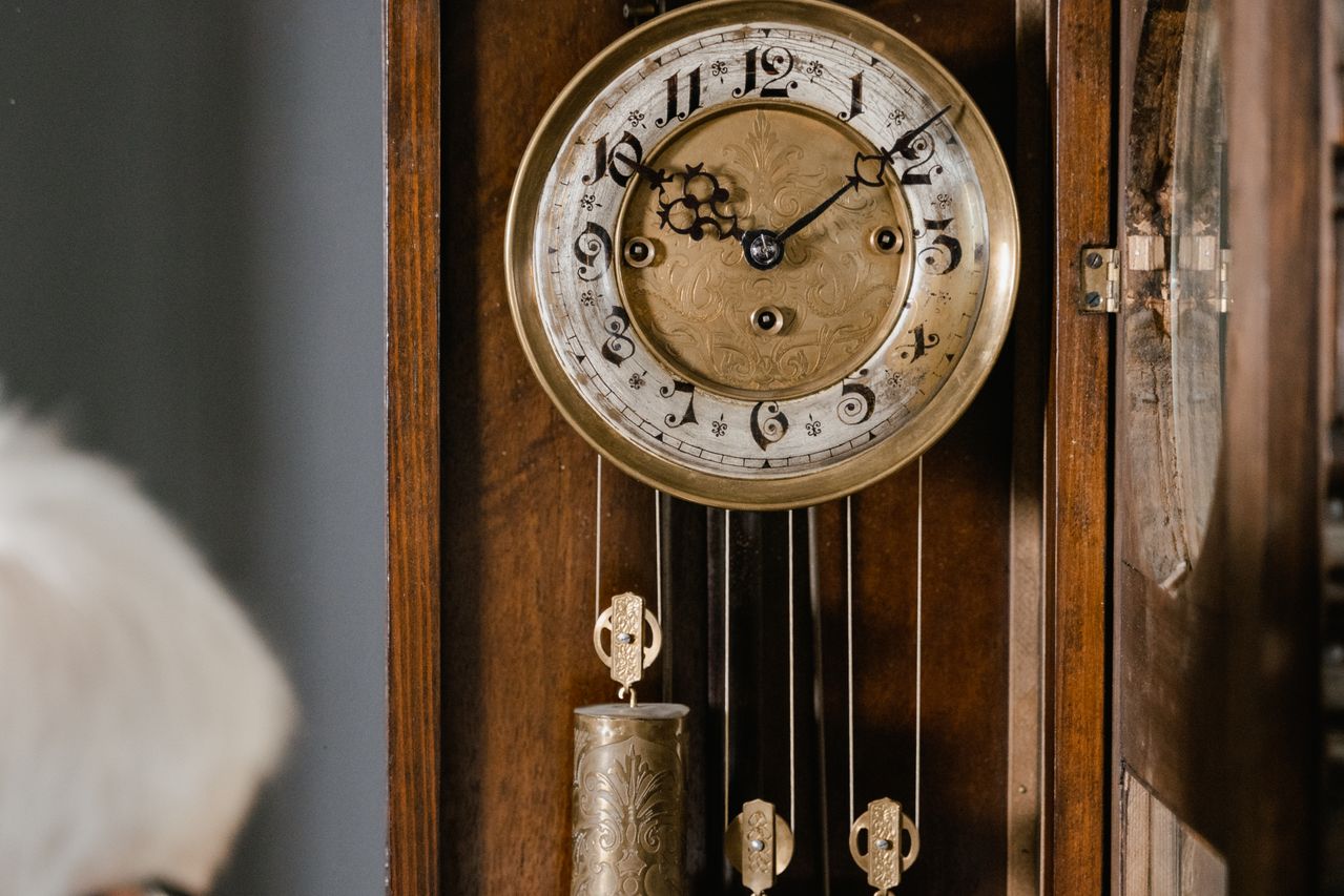 Antique pendulum clock with ornate brass dial and hanging weights