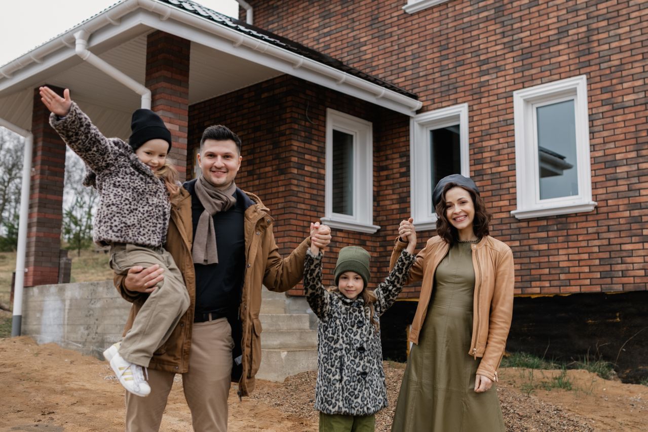 Happy family standing outside their suburban house