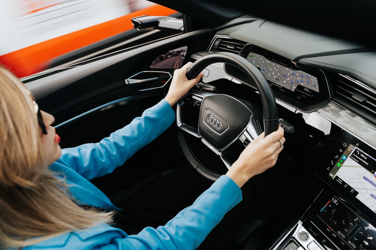 Driver steering an Audi electric SUV with a digital cockpit and touchscreen dashboard display