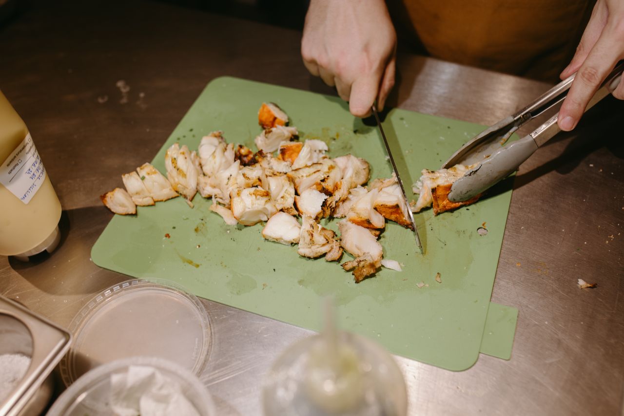 Hands slicing cooked chicken into bite-sized pieces for braces safety.