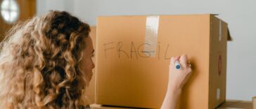 Woman labeling a fragile box during a relo g process