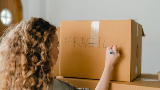 Woman labeling a fragile box during a relo g process