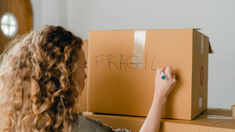 Woman labeling a fragile box during a relo g process