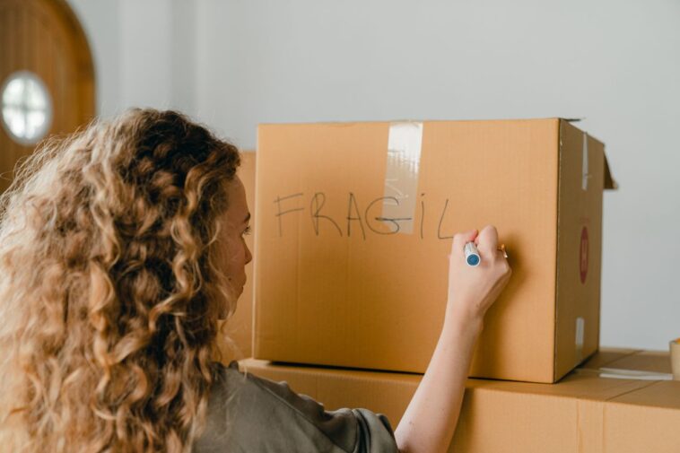Woman labeling a fragile box during a relo g process
