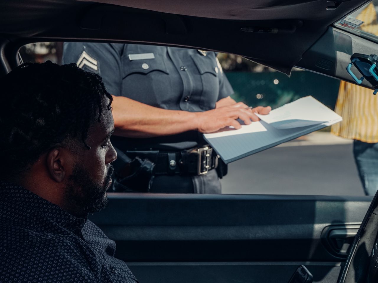 Driver receiving traffic citation from police officer at roadside stop