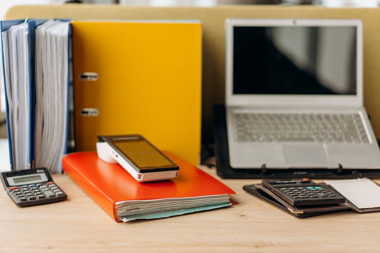 School administrative desk with binders and laptop for compliance work