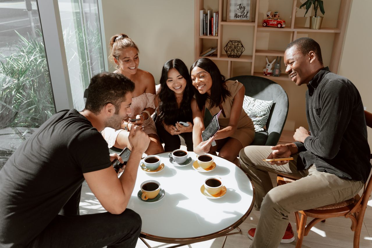 Diverse group collaborating around a community table with coffee.