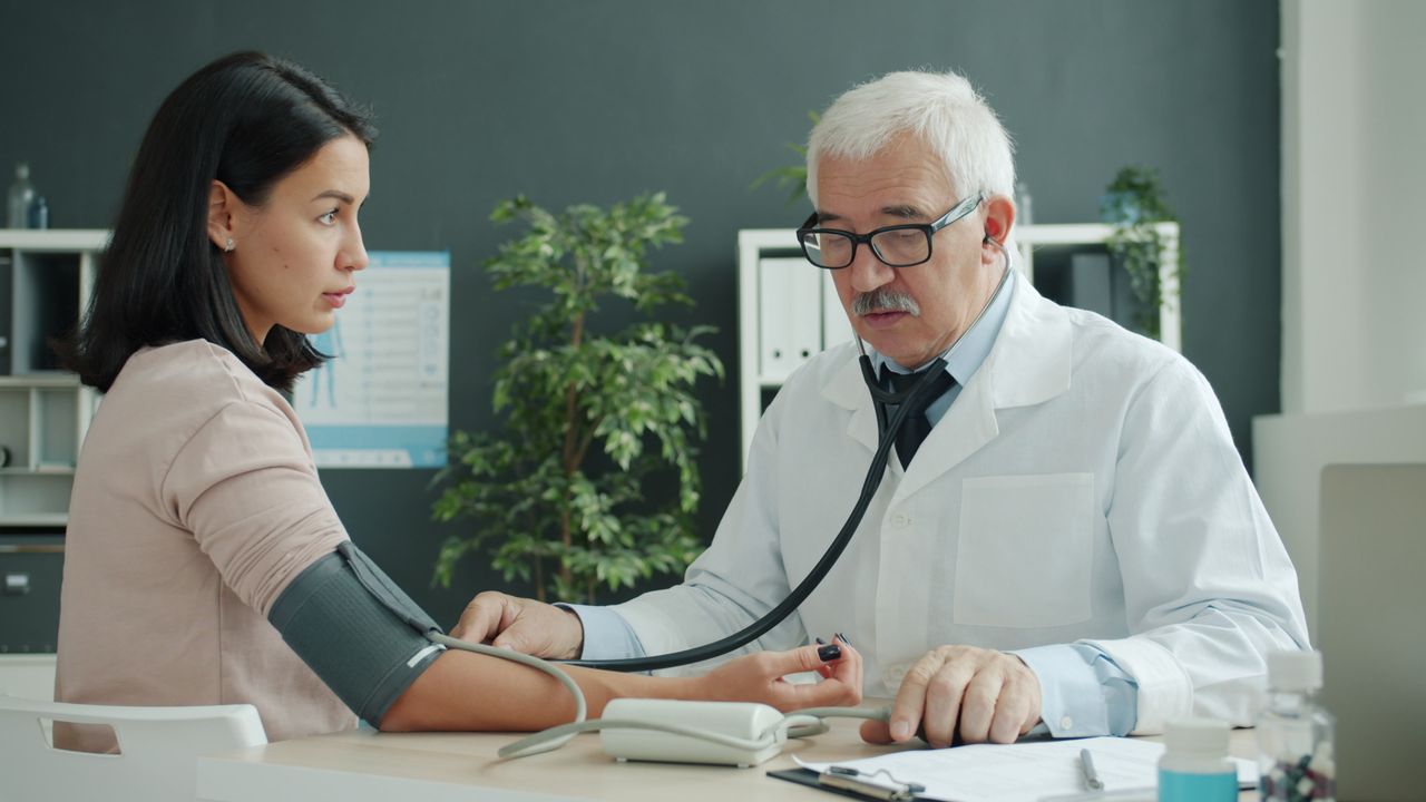 Doctor taking patient's blood pressure during a pre-employment physical exam