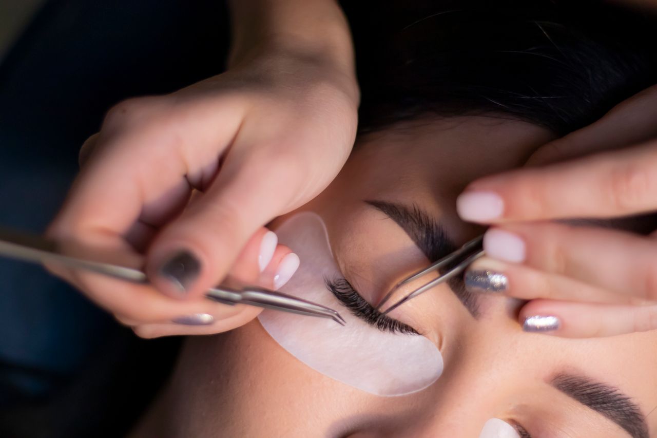 Lash artist applying an extension with precision tweezers.