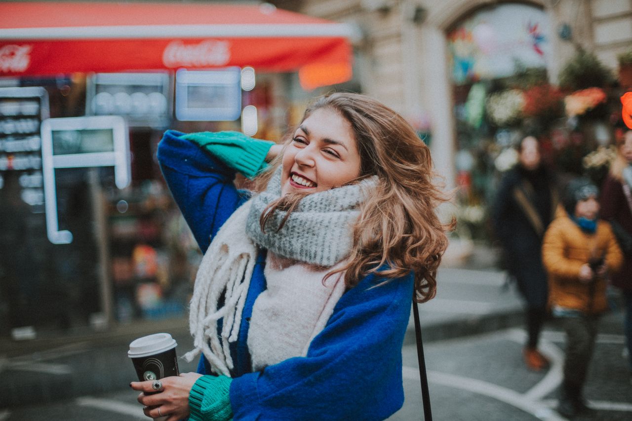 girl Layered winter outfit with sweater, coat, scarf and boots in a city