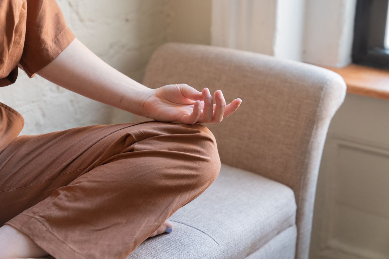 Hands resting on a lap during a mindfulness meditation breathing exercise in a quiet corner of a home