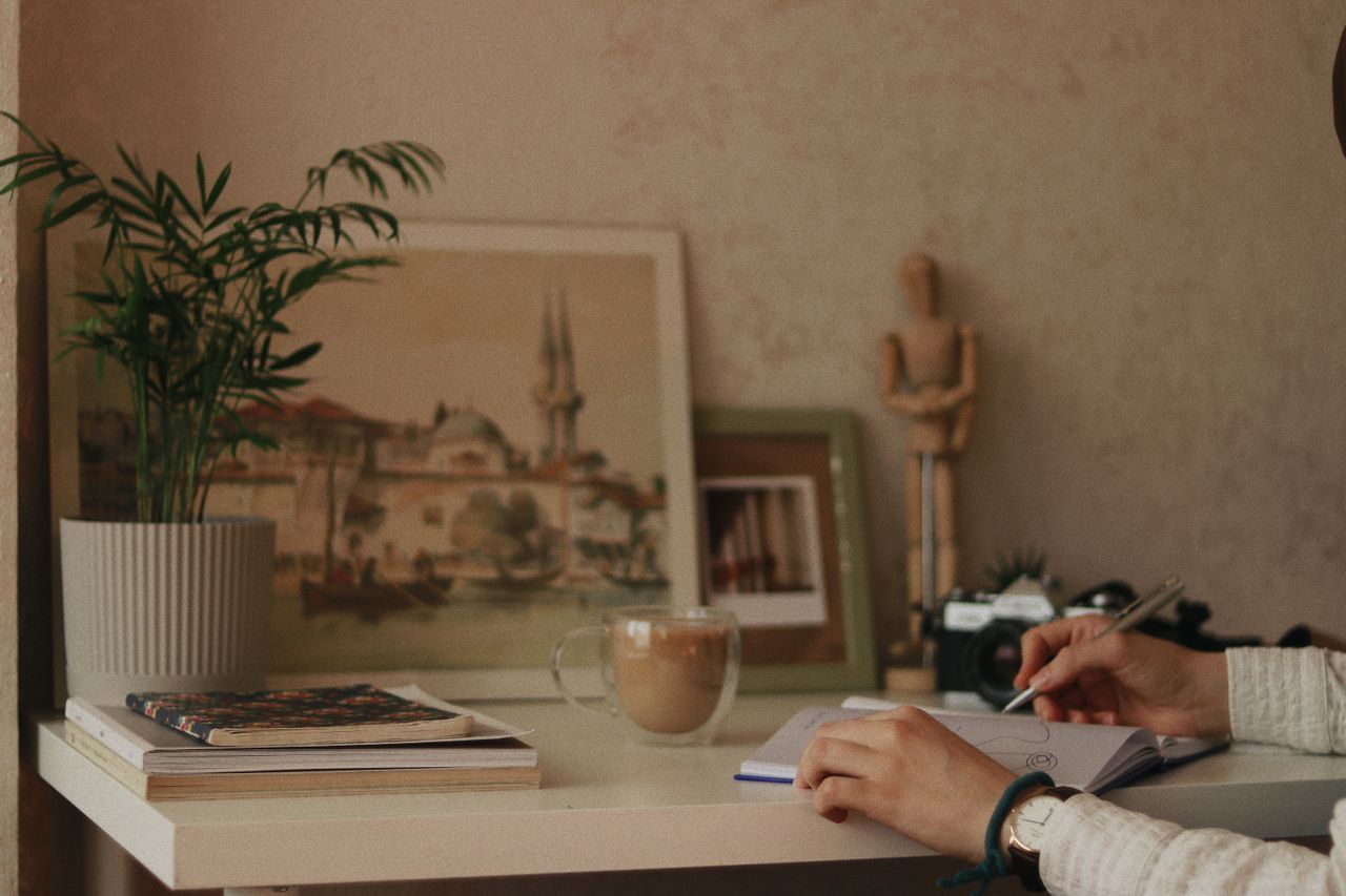 Person writing their reasons for working in a notebook at a desk