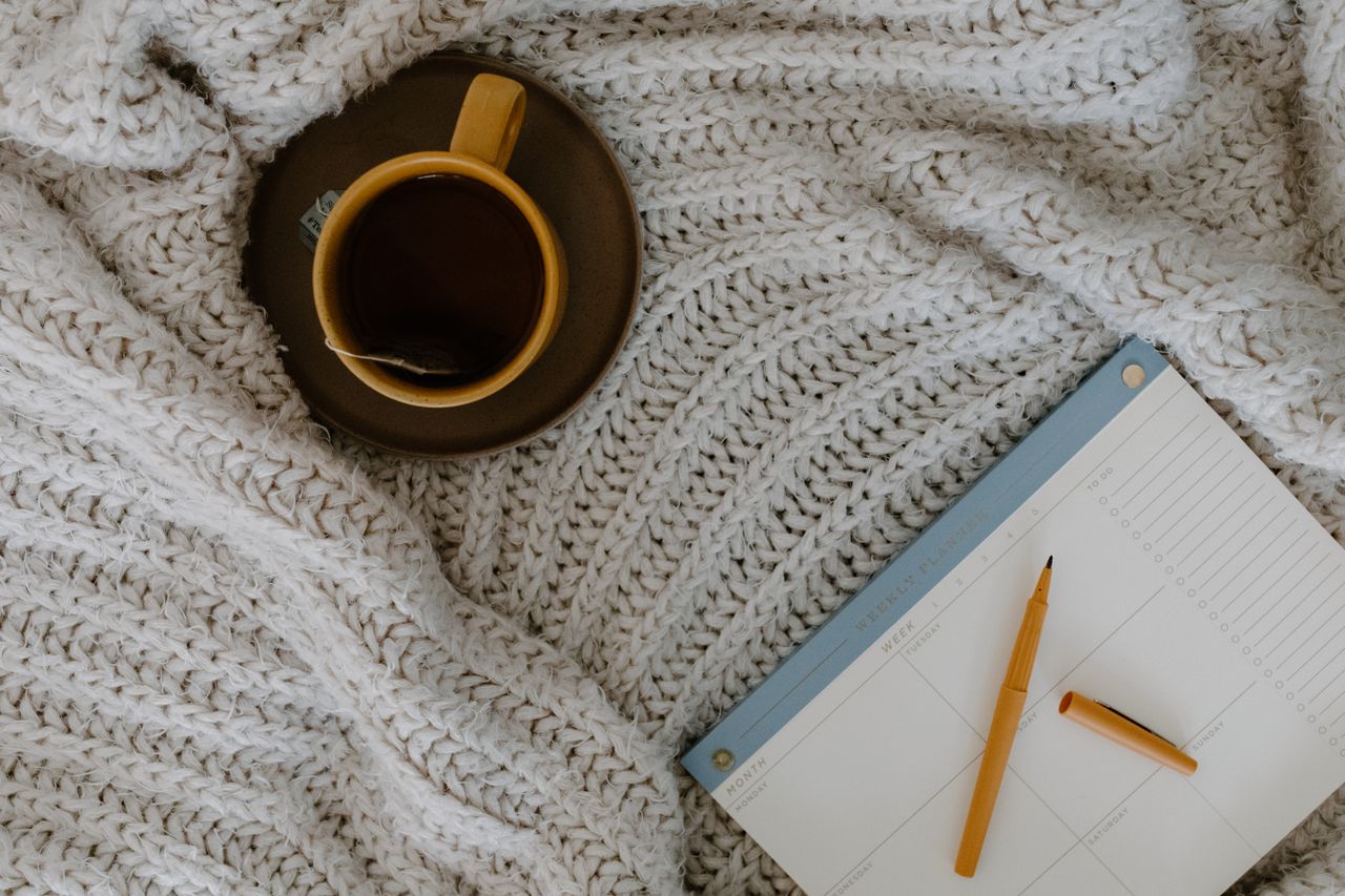 person filling in a worksheet or journal page beside a cup of coffee